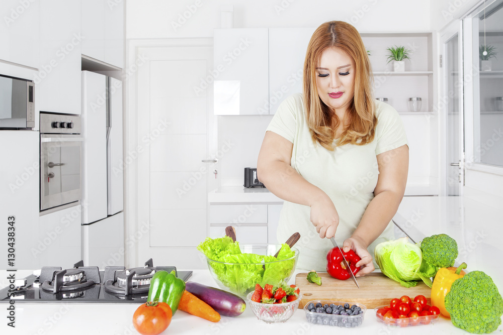 Obese woman cutting paprika