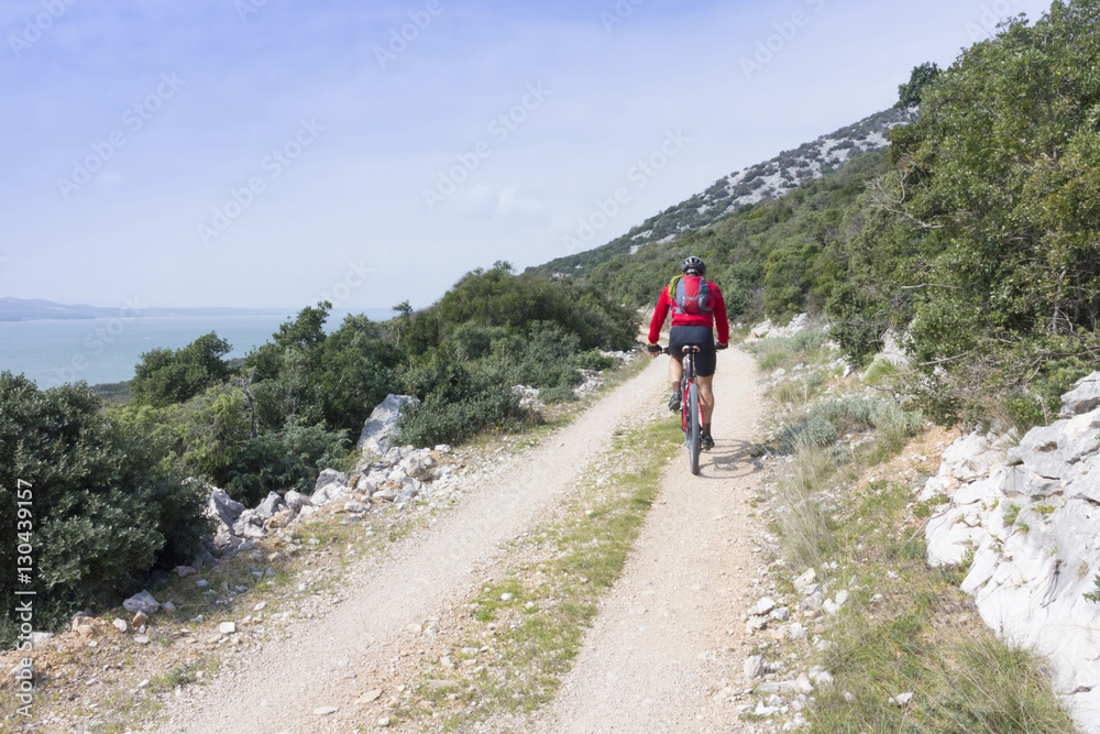 A mountain cyclist cycling around Vransko Jezero Lake, Dalmatia, Croatia A mountain cyclist cycling around Vransko Jezero Lake, Dalmatia, Croatia