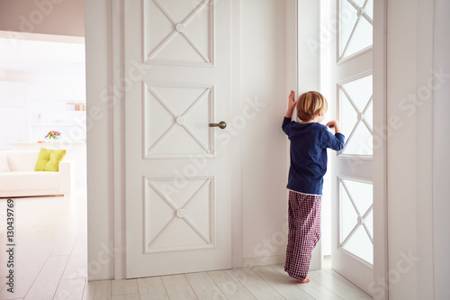 curious young boy looks into the ajar door © Olesia Bilkei