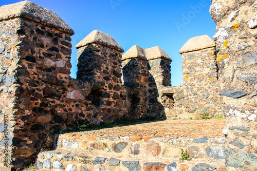 Castle wall with battlement and fortified tower in clear and sunny autumn day in a village named 