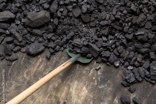 Black coal and shovel lying on a pile in house basement