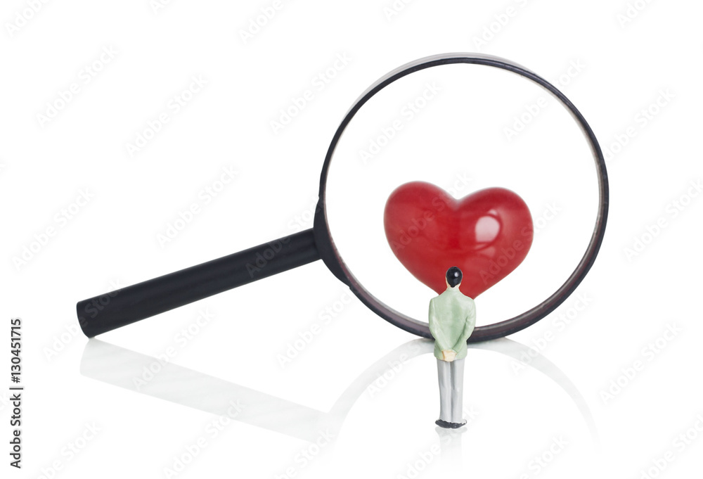 Figure man looking red heart through the magnifying glass Figure man looking red heart through the magnifying glass