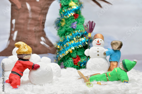 Puppet figures of children mold the snowman. Active outdoor recreation in winter. © Oleksandrum