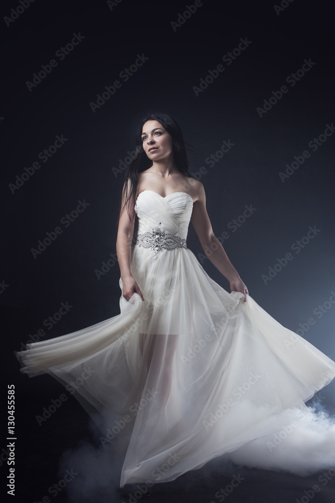 Beautiful sexy young woman. Portrait of girl in long white dress, mystical, mysterious style, dark background