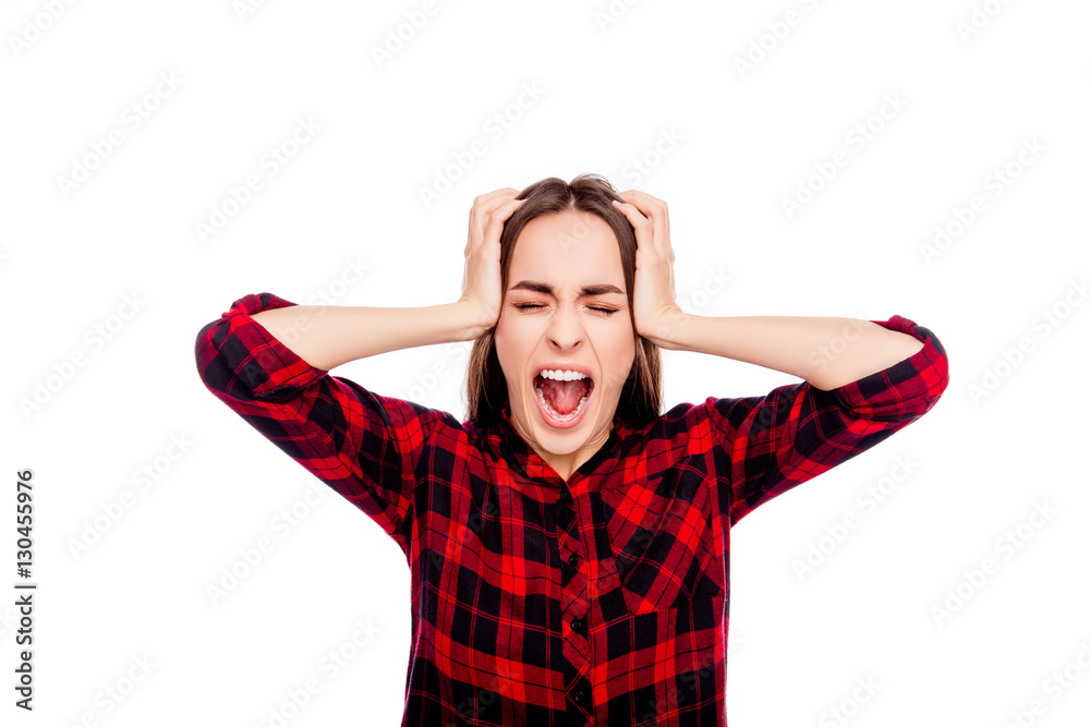Portrait of frustrated angry young woman touching head and screa