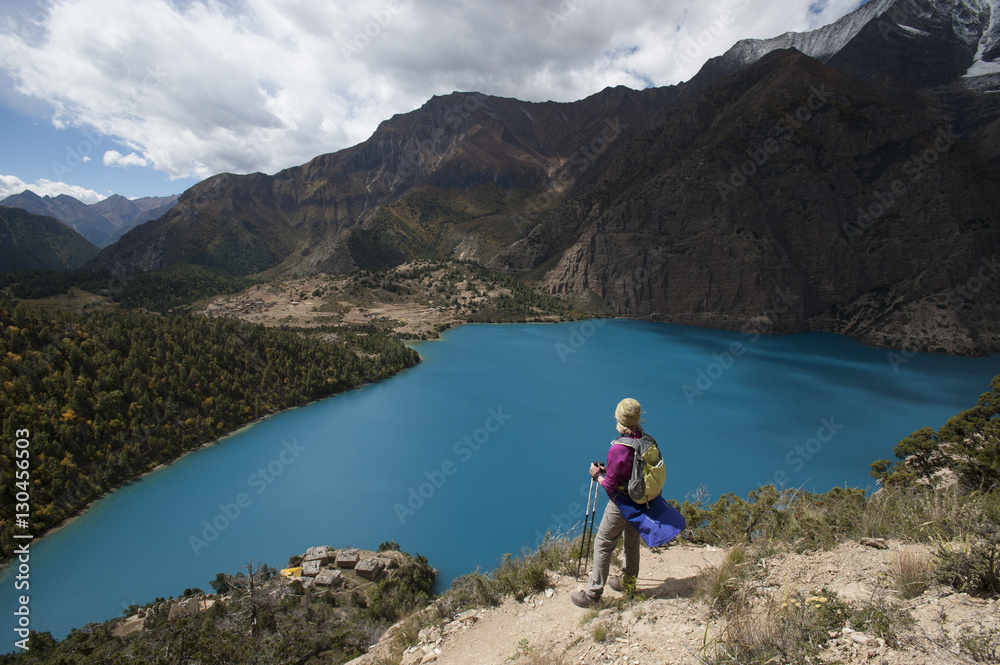 A trekker stands above the turquoise blue Phoksundo Lake in the Dolpa region, Himalayas, Nepal A trekker stands above the turquoise blue Phoksundo Lake in the Dolpa region, Himalayas, Nepal