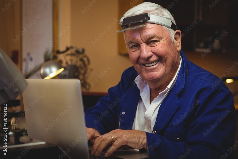 Horologist working on laptop in workshop Horologist working on laptop in workshop