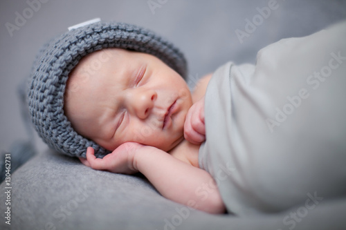 newborn boy in gnome dressed in a gray cap