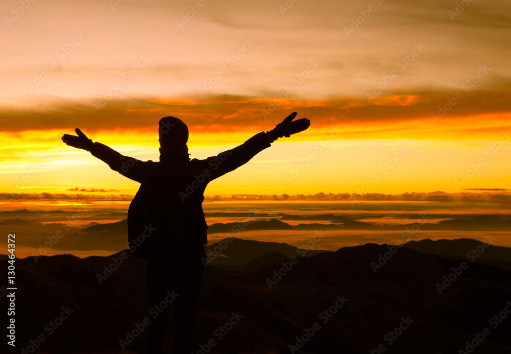 Happy woman standing on top a mountain enjoying the beautiful view. 