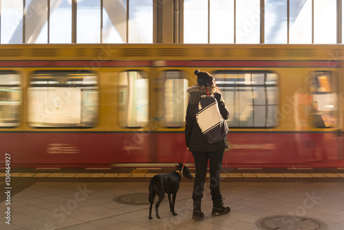 Woman and dog are waiting a train which was arriving at the platform of Metro station in Berlin, Germany during sunshine day photo