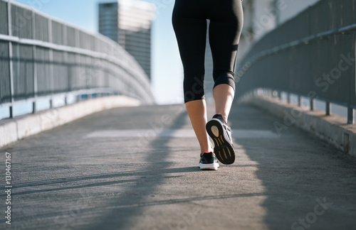 Closeup of woman runner running on city bridge. 