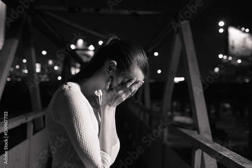 Young woman crying in a dark city setting. 