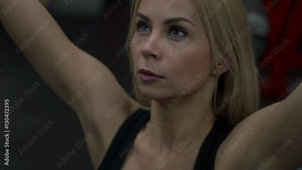 Blonde girl training at the gym. Woman engaged in fitness