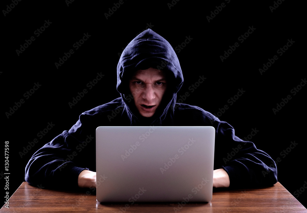 Hacker in a dark hoody sitting in front of a notebook Hacker in a dark hoody sitting in front of a notebook