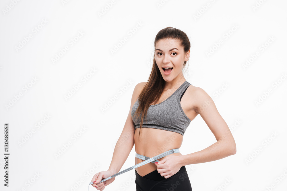 Happy surprised sports woman holding tape measure around her waist Happy surprised sports woman holding tape measure around her waist