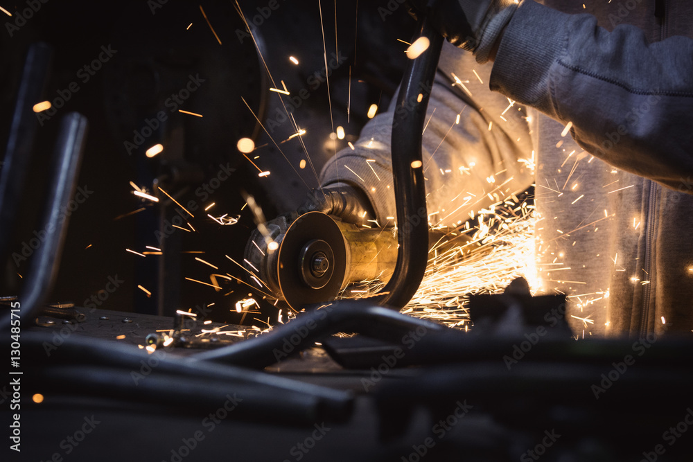 Metal grinding on steel pipe with flash of sparks close up