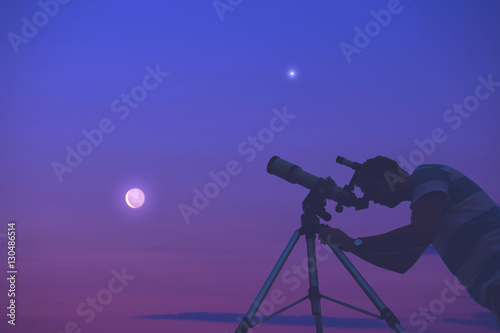Man looking at the night sky with telescope beside him.