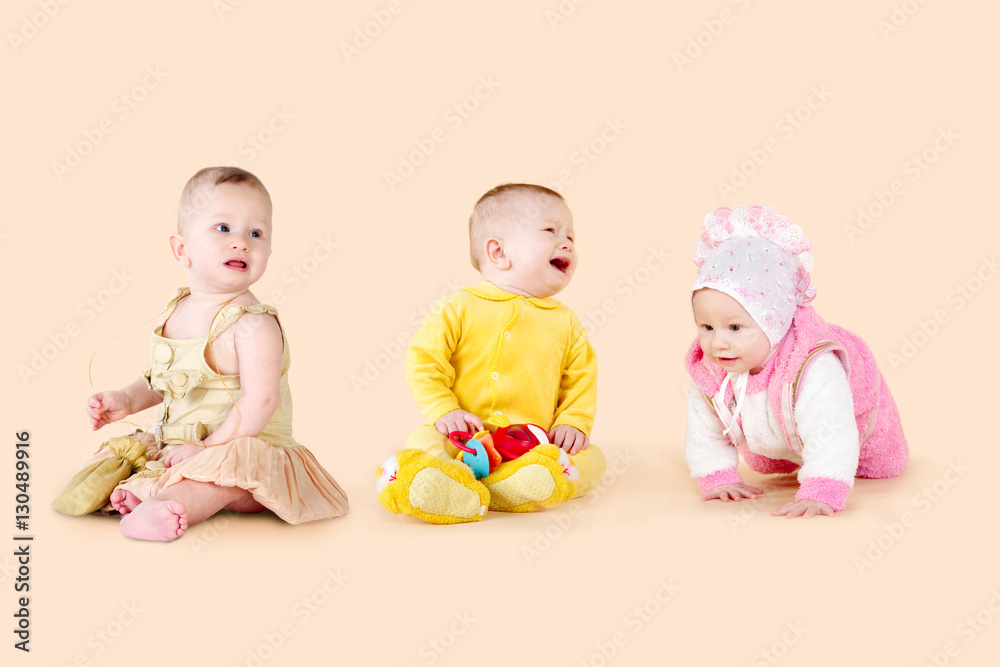 Babies on a beige background. Three children, different emotions and poses Babies on a beige background. Three children, different emotions and poses