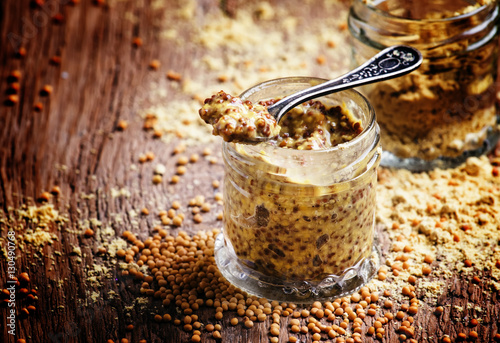 Mustard sauce with grains, old wooden background, selective focu