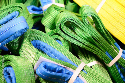 Green nylon soft lifting slings stacked in piles. photo