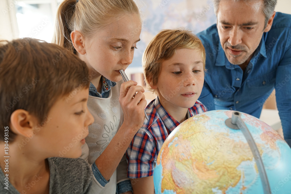 Teacher with kids in geography class looking at globe Teacher with kids in geography class looking at globe
