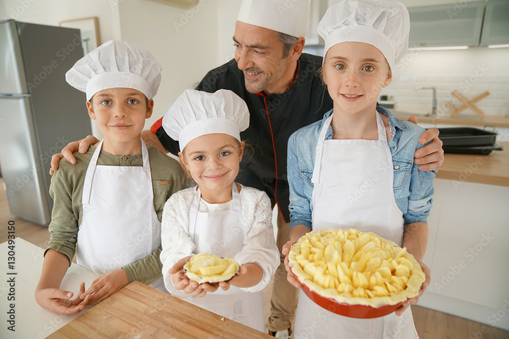 Portrait of pastry chef with pupils holding apple pie Portrait of pastry chef with pupils holding apple pie
