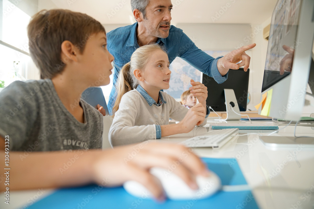 Fototapeta premium Teacher with school kids in computer laboratory