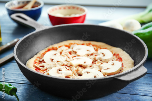Unbaked pizza in pan on wooden table