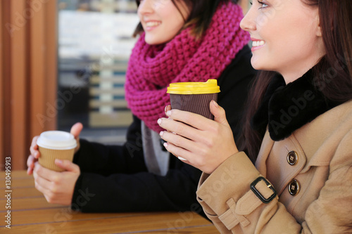 Cheerful young women drinki...
