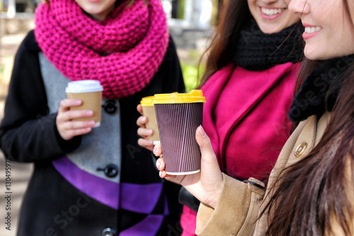 Cheerful young women drinking coffee outdoors