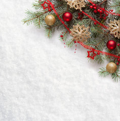 Fir branch with Christmas decorations on the background of natural snow.