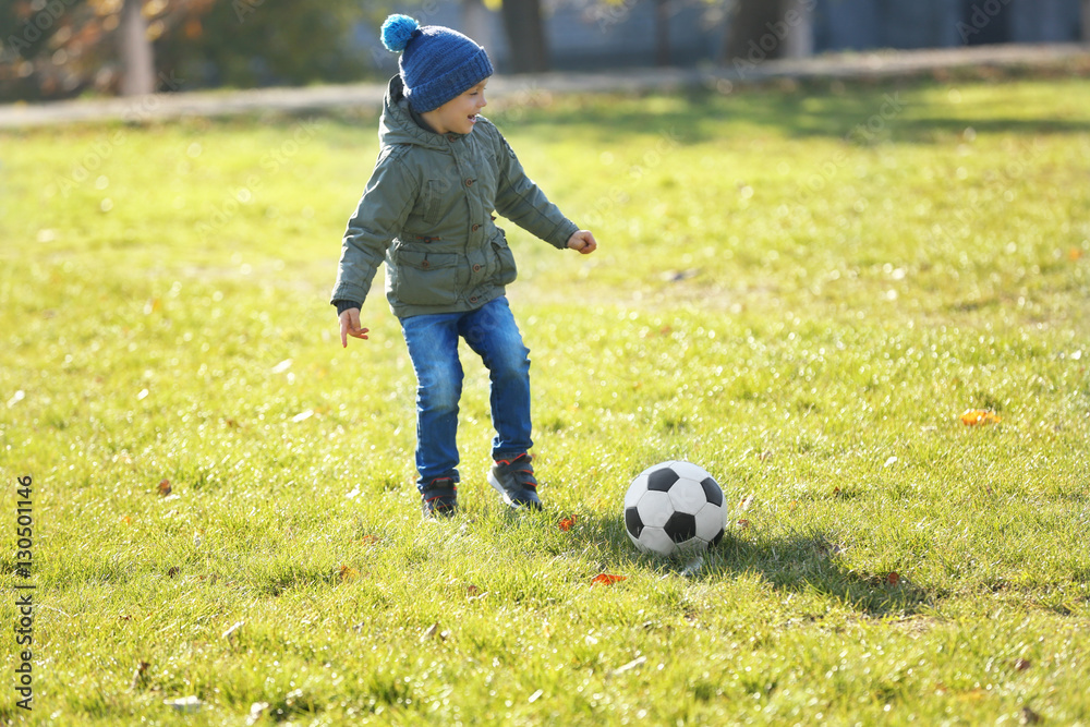Cute little boy playing football on soccer pitch Cute little boy playing football on soccer pitch