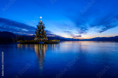 Fototapeta Naklejka Na Ścianę i Meble -  Christmas tree floating on a lake after sunset.