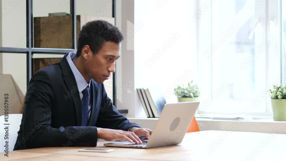 Black Businessman Upset by Loss while Working on Laptop Black Businessman Upset by Loss while Working on Laptop
