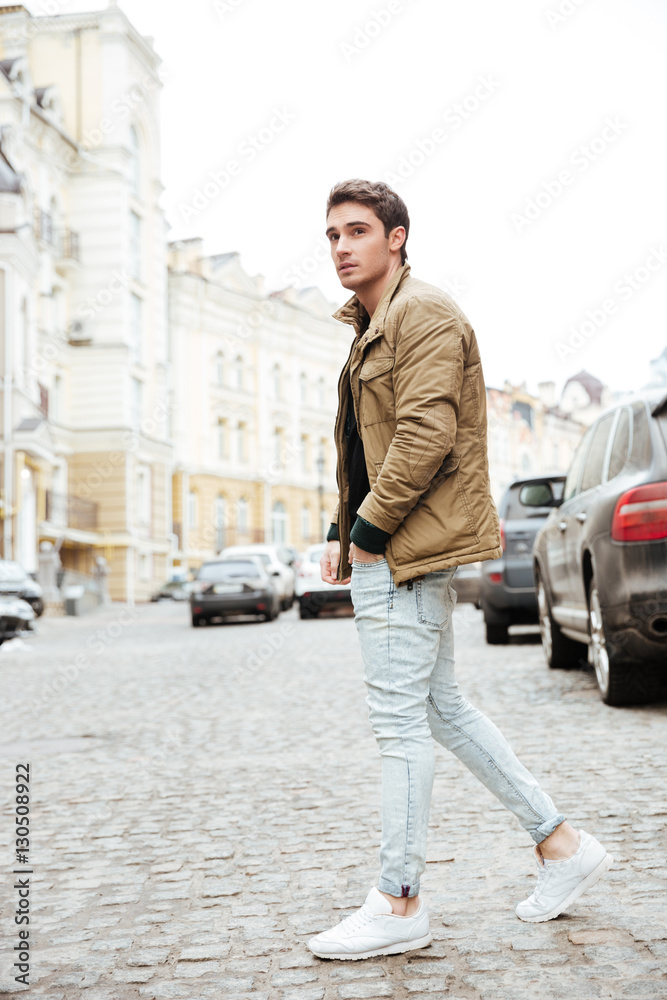 Young man walking on the street and looking aside.