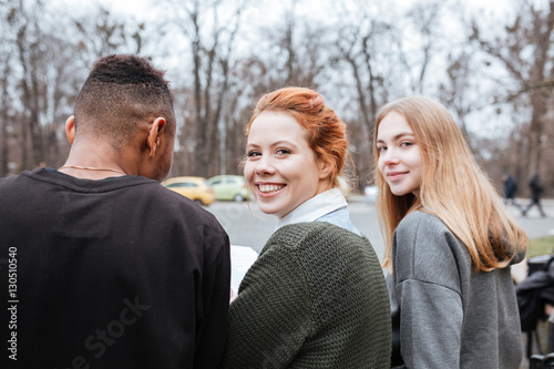 Group of young smiling teenagers sitting together outside © Drobot Dean
