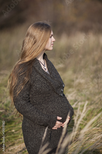 Junge Frau mit Babybauch auf herbstlicher Wiese