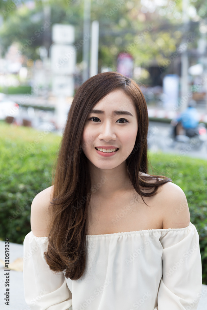 pretty asian girl in casual clothing is smiling with traffic in