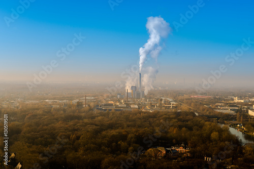 Industrie in der Landschaft mit rauchendem Schornstein und blauem Himmel