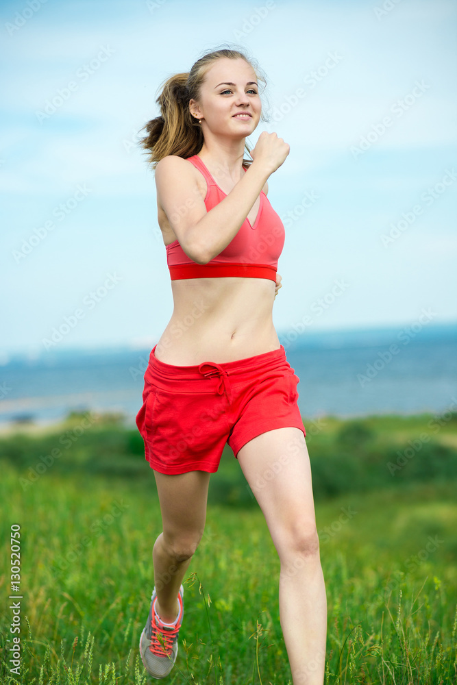 Young lady running. Woman runner running through the summer park rural road. Workout in a park. Beautiful fit girl. Fitness model caucasian ethnicity outdoors. Weight loss exercise. Jogging. Young lady running. Woman runner running through the summer park rural road. Workout in a park. Beautiful fit girl. Fitness model caucasian ethnicity outdoors. Weight loss exercise. Jogging.