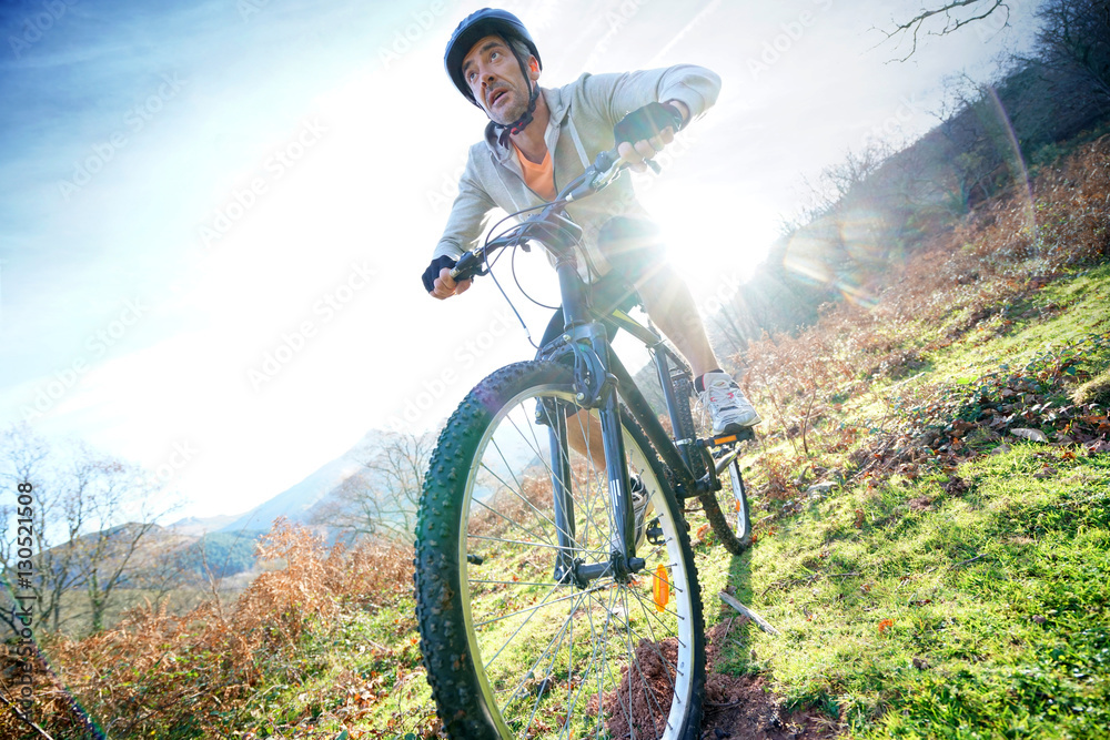 Fototapeta premium Mature man riding bike in the mountain