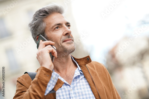 Mature handsome man in the street, talking on phone