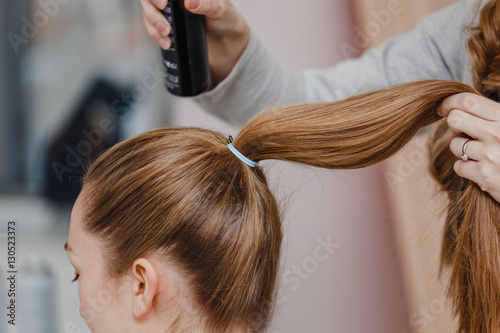 woman hairdresser combing golden healthy hair and collects them in a ponytail, hair preparing to further hairstyle