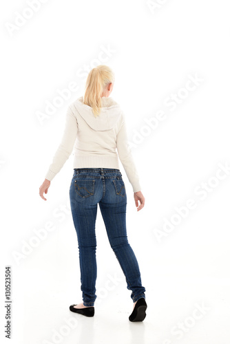 Full length portrait of a pretty girl wearing a casual white hoody and blue jeans. standing pose isolated against a white background.