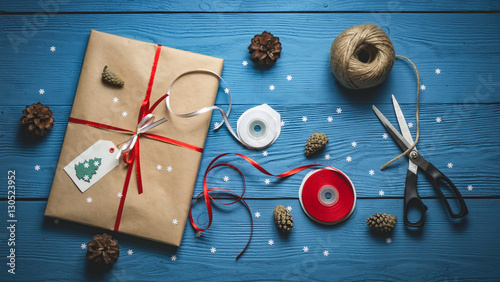 Gift packing handmade paper and red ribbon on blue wooden boards with white snowflakes photo