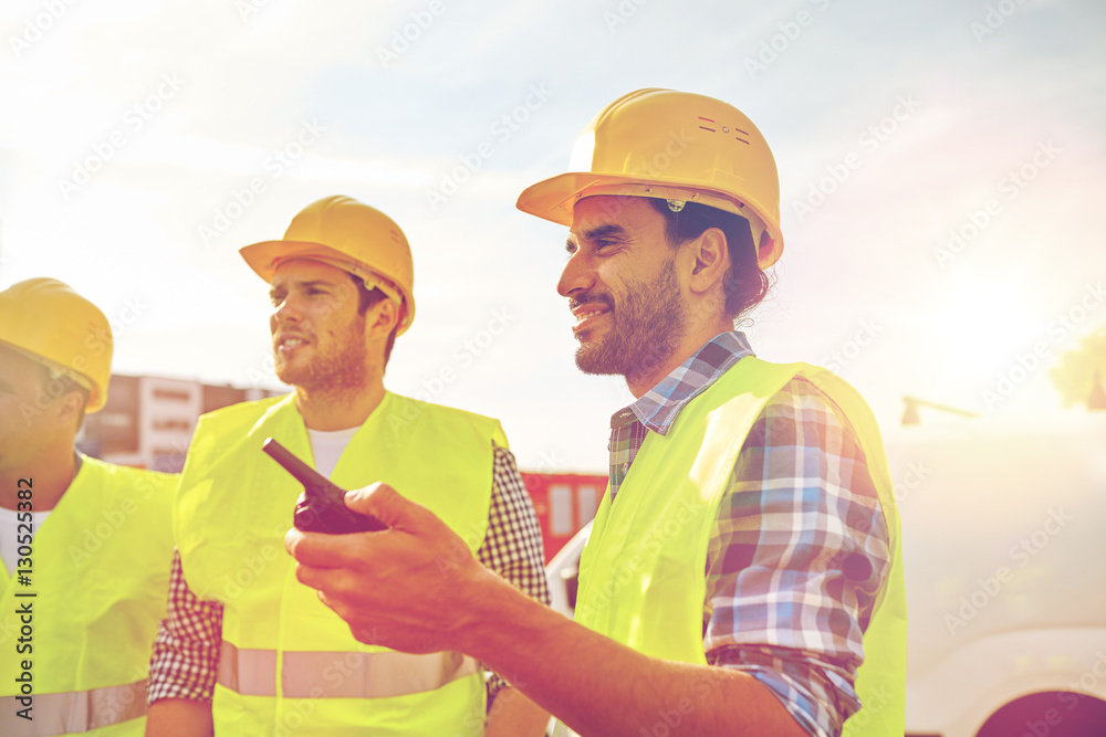 happy male builders in vests with walkie talkie happy male builders in vests with walkie talkie