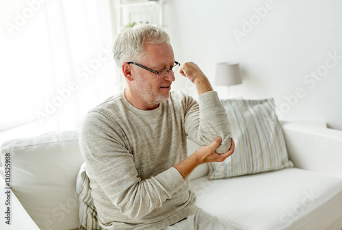 unhappy senior man suffering elbow pain at home