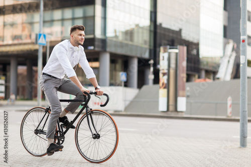 man with headphones riding bicycle on city street