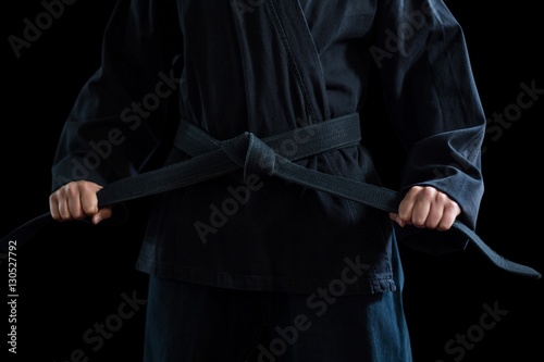Mid section of confident karate player holding his belt