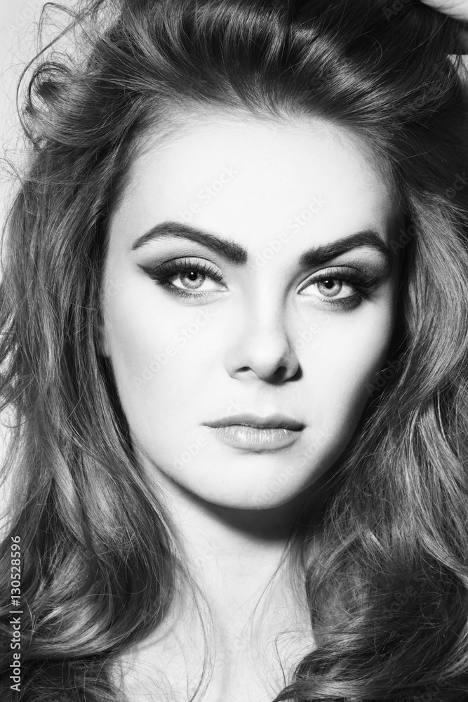 Black and white portrait of young beautiful girl with stylish winged eye make-up and long curly hair Black and white portrait of young beautiful girl with stylish winged eye make-up and long curly hair